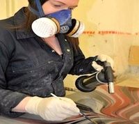 a woman in black shirt and white gloves waxing a car with blue mask on