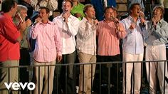 a group of men standing next to each other on top of a metal fence in front of a crowd