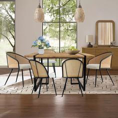 a dining table with four chairs and a vase on it in front of a large window