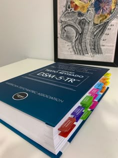 a book sitting on top of a white table next to a framed medical diagram in a black frame