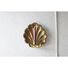 a gold scallop with a purple candle in it's center on a white wall