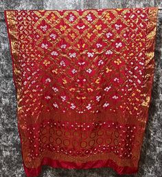 Rich Banarsi Ghatchola silk golden zari woven dupatta. This dupatta also has Bandhani hand tie dye design. It can be used for wedding dupatta, Odhani, with festival outfits, Lehenga dupatta, it is a multipurpose dupatta which goes with most of the things and occassions. It can also be used to gift to someone. This is a zari woven dupatta with full length there is no print on it. "This Banarsi Ghatchola silk dupatta features a stunning red color with intricate golden zari weaving and Bandhani han Gold Dupatta With Traditional Patterns For Eid, Gold Katan Silk Dupatta With Traditional Patterns, Gold Banarasi Silk Dupatta With Traditional Patterns, Festive Gold Dupatta With Traditional Patterns, Traditional Patterned Paithani Silk Dupatta For Navratri, Semi-stitched Gold Bandhani Print Saree, Gold Chanderi Dupatta With Traditional Patterns, Paithani Silk Dupatta With Traditional Patterns For Navratri, Navratri Traditional Pattern Paithani Silk Dupatta