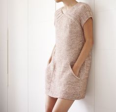 a woman leaning against a wall wearing a sweater dress