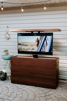 a flat screen tv sitting on top of a wooden cabinet in front of a house