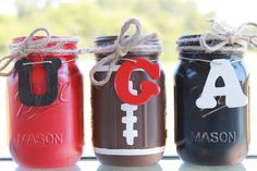 three painted mason jars are sitting on a window sill