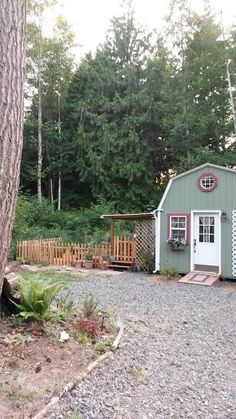 a small green shed sitting next to a tree