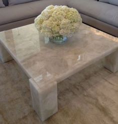 a white marble coffee table with flowers in a vase on it's centerpiece