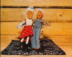 two dolls sitting on top of a rug