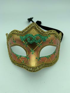 "This is a very nice original handmade and hand painted Venezia masquerade face mask made in Italy. The design on the shiny gold and orange face mask features turquoise blue and multi-color glitter with a border of gold lace and gold rope around the edges. It comes with a black ribbon tie and is stamped on the back \"Original Hand Painted Made in Italy Venezia\". The mask measures approximately 6 5/8\" long and 3 3/4\" wide and is in very good preowned condition with light wear on the back of th Fantasy Masquerade Mask For Carnival, Fantasy Masks For Carnival And Festivals, Fantasy Carnival Mask For Festivals, Adjustable Masquerade Mask For Mardi Gras, Mardi Gras Masks And Prosthetics, Fantasy Carnival Masquerade Masks, Hand Painted Masks And Prosthetics For Carnival, Fantasy Full Face Mask For Carnival, Artistic Masquerade Mask For Mardi Gras Carnival