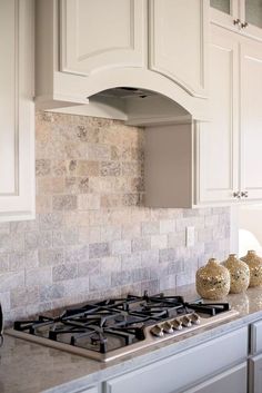 a stove top oven sitting inside of a kitchen next to white cabinets and counter tops