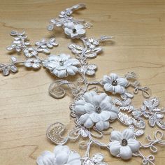 some white flowers on a wooden table and one is made out of metal filigrees