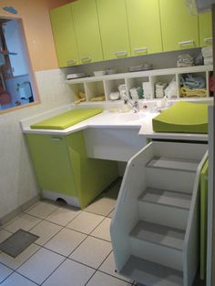 a bathroom with green and white decor on the walls, stairs leading up to the sink