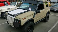 an off - road vehicle parked in a parking lot next to other cars and trucks