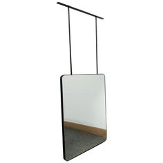 a mirror hanging from a metal rod on a white wall