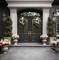 two large urns filled with pink flowers sitting in front of a black and white door