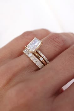 a woman's hand with two wedding rings on top of her finger and the ring is