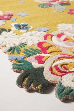 an area rug with colorful flowers and leaves on it's edges is laying on a white surface