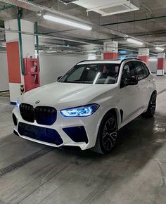 a white bmw suv parked in a parking garage