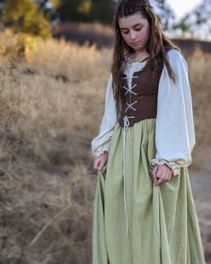 17'th century peasant-style dress. Made of 100% natural linen and cotton voile, this dress is a beautiful depiction of a typical working-woman's gown from the 1600-1700's. Bodice is lightly boned and made to fit snugly over the loose, full-sleeved blouse. The matching skirt fastens with a hook and eye closure and zipper in the back. Please note that the white fabric used will be slightly different than what the blouse is made of in the picture. Matching bodice and skirt sold in a separate listing: IMPORTANT! PLEASE NOTE WHEN CHOOSING A SIZE: Follow the diagram and chart when choosing your size. Make sure to measure around the widest part of your bust, your natural waist, around your arm at the socket, and your height from your natural waist to your ankle. Enter those measurements in the pe 1800s Peasant Dress, 1600s Dresses Peasant, Peasant Dress Aesthetic, Green Maid Dress, 1700s Dresses Peasant, 17th Century Dress Peasant, Cotton Dresses For Larp, Fitted Prairie Dress Costume For Medieval Festivals, Cotton Prairie Dress With Fitted Bodice