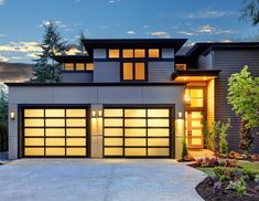 a modern house with two garages and lights on the front door at night time