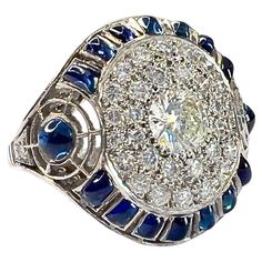 This Art Deco-style ring is crafted in platinum 950 and features Sapphires and Diamonds. It has a weight of 7.5 grams and is sized 16/56. The Diamonds are brilliant-cut, with a central stone of 0.50 carats and a total weight of 1.22 carats. They are of VS-SI clarity and G-H color grade. The Sapphires are cabochon-cut and other custom cuts to fit the piece. The gemstones are set in a grain setting, and the front motif measures 2 cm x 2 cm. ** IN STOCK** Characteristics: Material: Platinum 950 Central Diamond: 0.50 ct, Brilliant Cut Total Diamonds: 1.22 ct total, Brilliant Cut, VS-SI Clarity, G-H Color Sapphires: Cabochon and Custom Cuts Weight: 7.5 grams Ring Size: 16/56 Setting: Grain Front Motif Dimensions: 2 cm x 2 cm Art Deco Drop Earrings, Vintage Cluster Ring, Art Deco Diamond Rings, Blue Sapphire Diamond, Gold Art Deco, Rise Above, Estilo Art Deco, Art Deco Diamond, Art Deco Ring