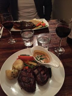 a person sitting at a table with plates of food and glasses of wine in front of them