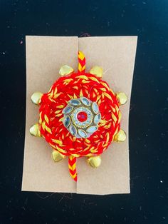 a red and yellow object on top of a brown piece of paper next to thread