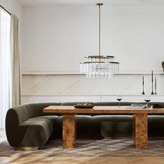 a living room with a couch, table and chandelier hanging from the ceiling