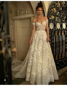 a woman standing in front of a gate wearing a wedding dress