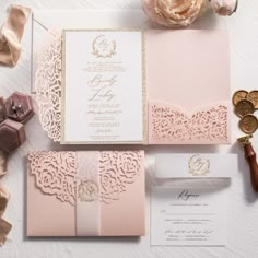 the wedding stationery is laid out on top of each other, including a pink and gold pocketfold