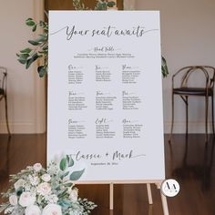 a seating chart with flowers and greenery sits on top of a wooden easer