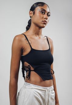 ArtcareShop's new take on a cut out top.  *Side cuts with strings to tie *Spagetti straps  *Petite fit (the model is wearing a size M). Size S Petite - chest 31.9in, length 16.5in Size M Petite - chest 33.4in, length 16.9 in Size L Petite - chest 34.9in, length 17.3in Size XL Petite - chest 36.4in, length 17.7in  Our favorite black  95% cotton and 5% polyester thick fabric (the same as our oversized t-shirts, biker shorts sets and Kai open back turtleneck). The model is wearing a size Petite M. ---------------------------------- ArtcareShop is a women-owned streetwear brand. From street to seam, we seamlessly blend edgy athleisure streetwear with luxurious designer quality to offer you a truly unique and effortless wardrobe that empowers you. Why Choose Us? * Crafted with Love: ArtcareShop Stretch Tops With Spaghetti Tie Straps, Fitted Strappy Tops With Tie Straps, Stretch Spaghetti Strap Top With Tie Straps, Stretchy Spaghetti Strap Top With Tie Straps, Casual Strappy Tops With Tie Back, Casual Strappy Tie-back Tops, Fitted Top With Multiple Tank Straps, Black Cotton Top With Tie Straps, Black Cotton Tops With Tie Straps