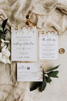 the wedding stationery is laid out on top of a blanket with flowers and greenery