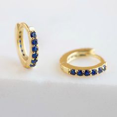 "An all-time bestseller with dark blue sapphire zirconia stones. Elegant and classic, these tiny huggie hoops prong-set with brilliant zirconia gemstones are a beautifully dainty addition to your everyday lineup. Subtle, versatile and perfect to mix and match with other earrings. * D E T A I L S * ∙ Sold individually (1 earring) or as a pair (2 earrings) ∙ Material: .925 Sterling Silver or 18K Gold Plated over .925 Sterling Silver ∙ Stone: Blue Zirconia ∙ Dimensions: Hoop Diameter: 10mm // Width Blue Huggie Hoop Earrings, Blue Small Hoop Huggie Earrings, Hypoallergenic Blue Small Hoop Huggie Earrings, Blue Hypoallergenic Small Hoop Huggie Earrings, Blue Small Hoop Huggie Earrings For Everyday, Blue Huggie Hoop Earrings For Pierced Ears, Blue Hoop Huggie Earrings Gift, Blue Huggie Hoop Earrings For Gift, Blue Huggie Hoop Earrings As Gift