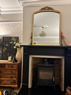 a woman standing in front of a fireplace with a mirror on it's mantle