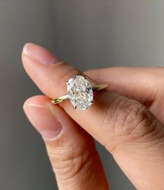 a close up of a person's hand holding a ring with a diamond on it