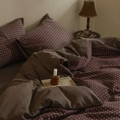 a bottle of medicine sitting on top of a bed next to pillows and a lamp