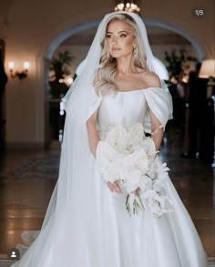 a woman in a white wedding dress holding a bouquet and posing for a photo on her wedding day