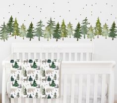 a baby crib next to a wall with trees on it