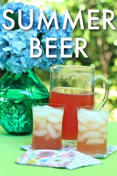 three glasses filled with liquid sitting on top of a table next to a pitcher and vase