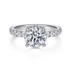 a round brilliant cut diamond engagement ring with pave set diamonds on the band and side stones