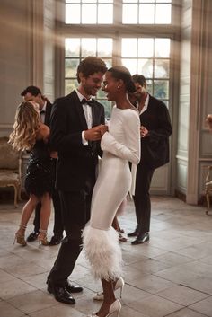 a man and woman dance together in an elegant room with other people standing around them