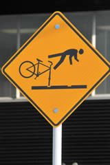 a yellow street sign with a bicycle on it's side and a building in the background