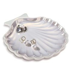 a white shell shaped tray with two pairs of earrings on the bottom and an earring in the middle