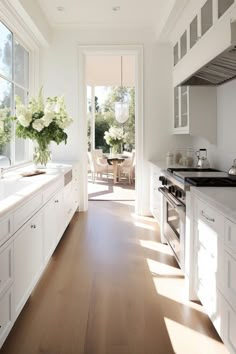 a kitchen filled with lots of white cabinets and counter top space next to a wooden floor