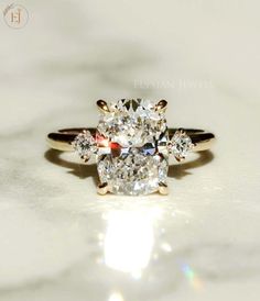 a three stone diamond ring sitting on top of a white surface with the light shining through it