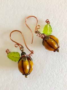 "Darling roasted orange pumpkin Czech glass melon beads wire wrapped with green leaves and copper tendrils on handmade ear wires. Beautiful 12mm opaque Czech glass melon beads in roasted orange squash color with rustic Picasso glaze are wire wrapped with embossed bronze bead caps, Czech olive green glass leaves and copper wire tendrils. Earrings hang from handmade copper ear wires. Total drop is 1 1/2\". Perfect fall accessory!" Artisan Orange Copper Earrings, Handmade Orange Copper Earrings, Orange Copper Wire Wrapped Jewelry, Bead Pumpkin, Paris Charm Bracelet, Diy Earrings Dangle, Pumpkin Idea, Thanksgiving Earrings, Aquamarine Earrings