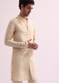 Introducing our regal beige embroidered sherwani set, a stunning amalgamation of elegance and grandeur. Highlighted with intricate cutdana, and hand embellished zardozi work, the sherwani is further accentuated with a stylishly designed high collar. Paired with a complementing kurta and pants, this silk outfit adds a modern twist to your traditional ensemble. Dry-clean only if required. Slight variation in color is possible due to digital photography. Cream Long Sleeve Churidar With Cutdana, Formal Beige Sherwani With Chikankari Embroidery, Designer Beige Kurta With Cutdana, Elegant Cream Kurta With Cutdana Detailing, Designer Beige Cutdana Kurta, Elegant Cream Kurta With Cutdana, Festive Beige Designer Churidar, Formal Beige Traditional Wear With Chikankari Embroidery, Long Sleeve Raw Silk Kurta For Transitional Season