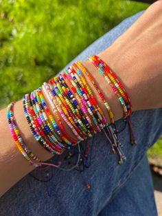 a person is sitting on the ground with their arm wrapped in bracelets that are multicolored