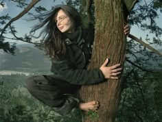 a woman climbing up the side of a tree with her hands on top of it